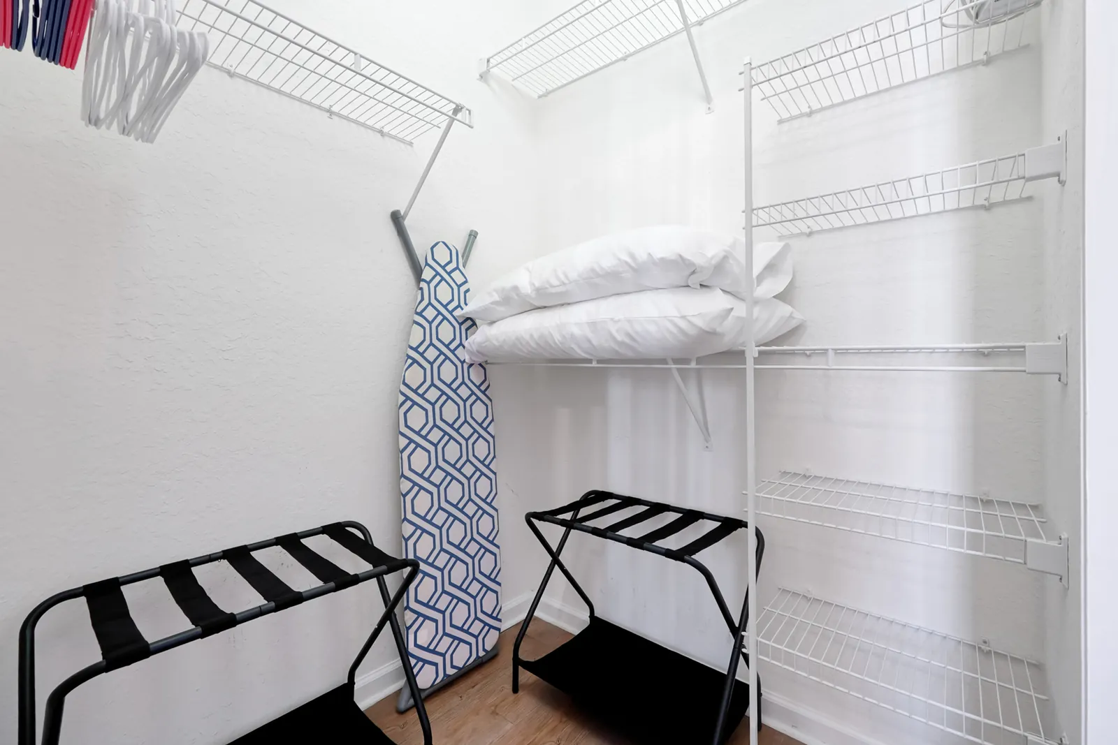 Master bedroom closet with luggage racks, hangers, and extra pillows