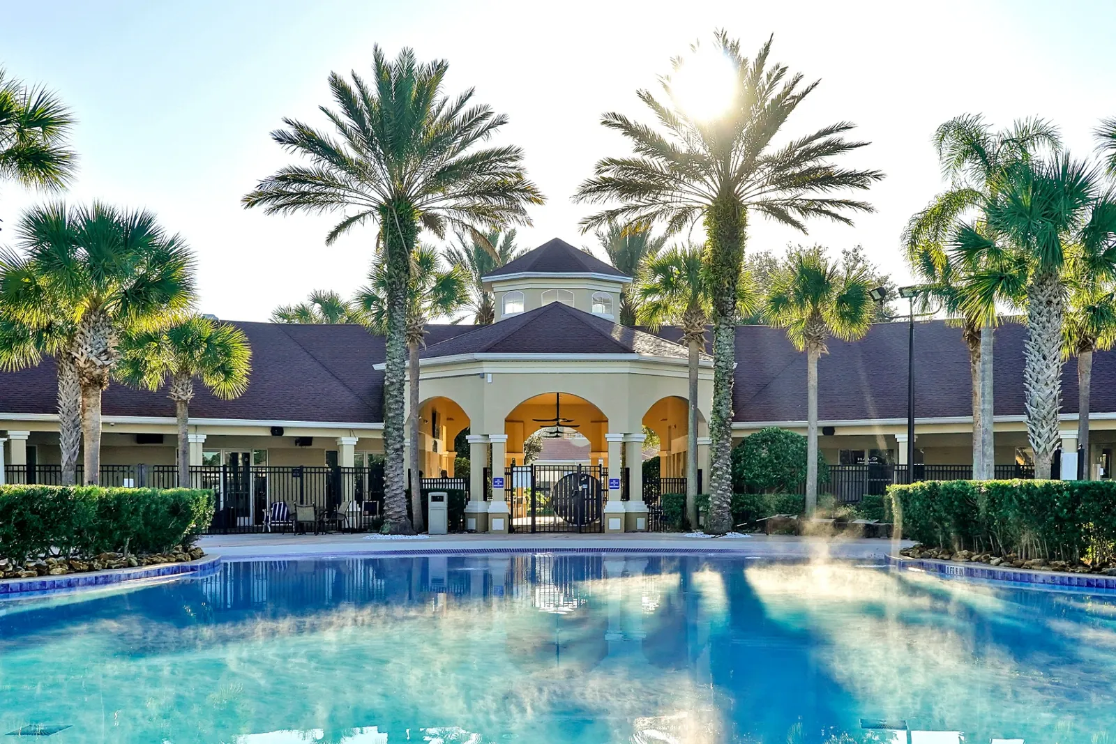 Clubhouse pool framed by palm trees in the morning sun